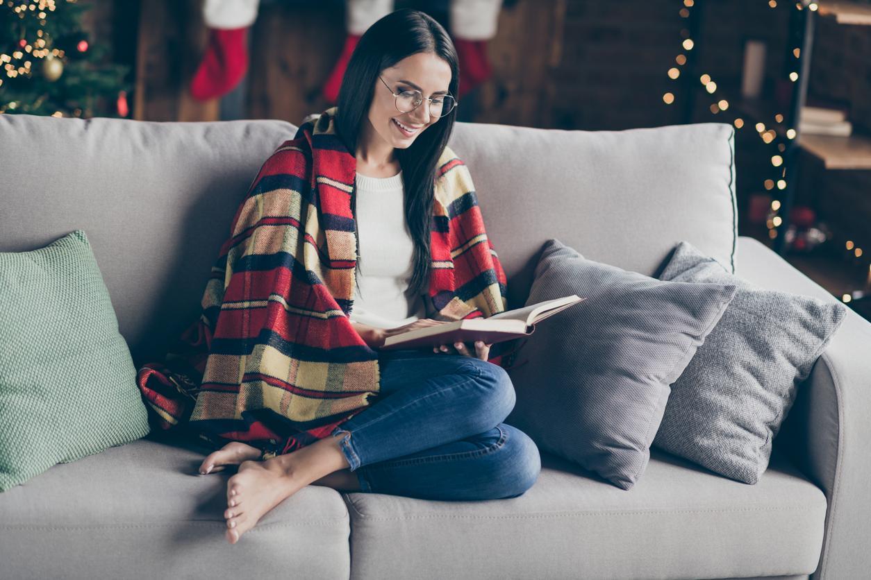 Žena na gauči čte knihu a užívá si vánoční svátky